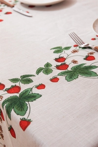 Close-up of red strawberry print on linen-cotton tablecloth with draped edge detail