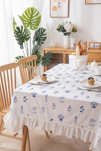 Close-up of blue floral embroidery on white cotton tablecloth with ruffled hem detail