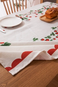Close-up of strawberry print tablecloth with red wavy edges and textured linen fabric