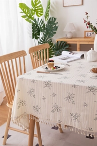 Close-up of floral cotton tablecloth with beige fringes and purple botanical print