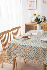 Detailed close-up of pom-pom tassel fringe on cotton linen tablecloth with persimmon print