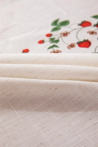 Close-up of linen fabric showing strawberry pattern and detailed weaving texture