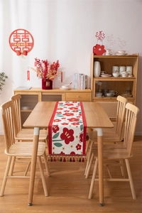 Detail van bloemstijl tafelloper met rode pruimbloesems en decoratieve kwastjes
