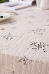 Close-up of lavender floral print on beige cotton tablecloth with woven texture