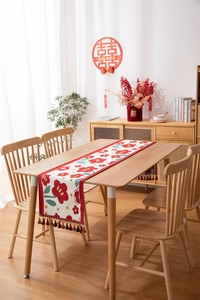 Detailweergave van bloemen tafelloper met kleurrijke kwastjes op rustieke houten tafel