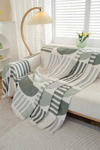 Detail view of the green geometric waffle textured sofa throw blanket with fringed edges