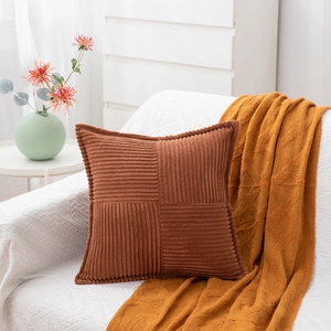 Detail of rust red corduroy pillow cover with striped patchwork texture on sofa