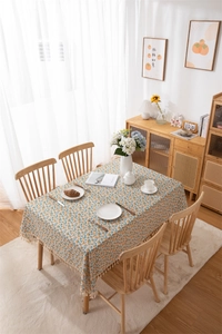 Detail of rectangular cotton linen tablecloth with orange floral print and tassel edges