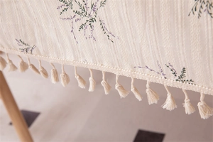 Close-up of cotton floral tablecloth showing purple lavender print and beige tassels