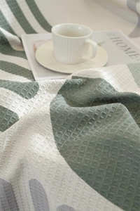 Detail of green and white waffle weave sofa throw showing soft texture and tassel edges