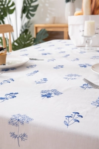 Close-up of blue floral embroidery on white cotton tablecloth with ruffled edges