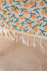 Detail of cotton linen tablecloth with orange citrus print and delicate lace fringe edges