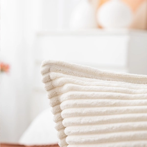 Macro detail of cream corduroy cushion cover showing soft striped texture and stitching