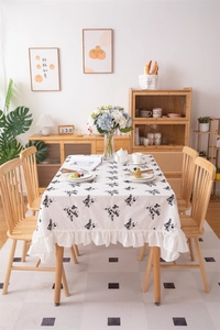 Detail of floral cotton tablecloth with black embroidery and elegant ruffled edges