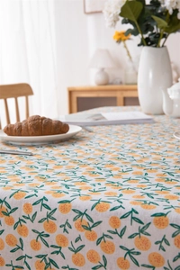 Detail of orange and leaf print on beige cotton linen tablecloth with fringe texture