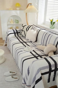 Close-up of waffle weave texture and fringe detail on the black and white plaid sofa cover