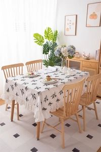 Detail of white cotton tablecloth with black floral embroidery and ruffled edges