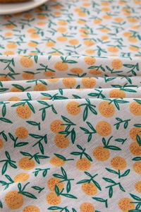 Close-up of leaf and orange printed linen fabric with natural cotton fringe detail