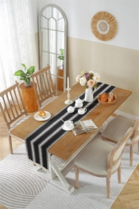 Detail of woven geometric boho table runner featuring black stripes and white tassels