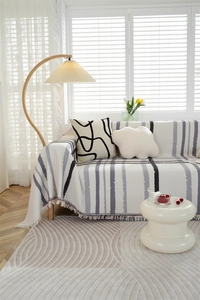 Close-up of geometric waffle weave sofa cover with tassels and textured rug in cream tone