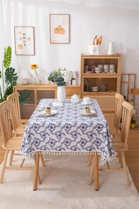 Detail of blue botanical vine prints and white fringe tassels on linen tablecloth