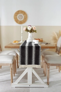 Close-up of bohemian table runner featuring black and white geometric patterns and tassels