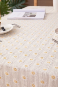 Close-up of pastoral cotton tablecloth with daisy embroidery and striped texture details