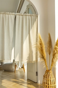 Close-up of beige cotton linen striped curtain with detailed tassel fringe on bottom edge