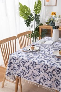 Close-up of leaf print tablecloth with white fringe tassels on a dining table
