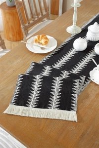 Close-up of cotton linen table runner with geometric patterns and white tassels