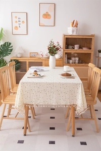 Detail of cream rectangle tablecloth with sunflower patterns and white fringe tassels