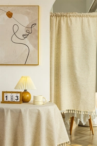 Close-up of warm beige linen fabric texture with elegant tassel edges and natural weaving