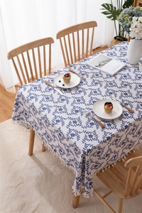 Detail of blue floral print tablecloth with elegant white tassels on a cotton linen fabric