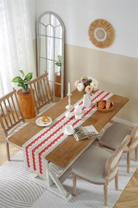 Detail of red wavy embroidery and fringe tassels on a cream cotton linen table runner