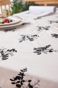 Close-up of black floral embroidery on a white cotton tablecloth with ruffled edges