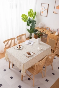 Detailed close-up of cream floral cotton tablecloth featuring elegant fringe tassel edges
