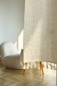 Close-up of cream cotton door curtain with vertical stripes and handmade tassel edge