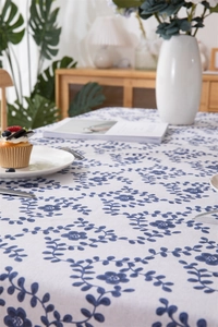 Detailed view of white cotton-linen tablecloth with blue floral vine pattern and fringe