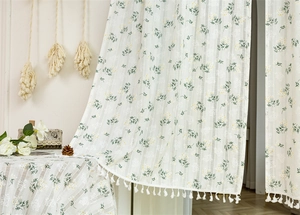 Detail of white cotton lace curtain featuring floral daisy pattern and fringe trim edge