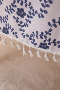 Detail of leaf print tablecloth featuring elegant white tassels and linen texture