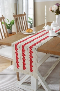 Detail of cotton linen table runner with red heart embroidery and tassel accents