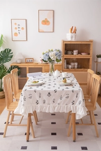 Detail of white cotton tablecloth with black floral embroidery and ruffled edges