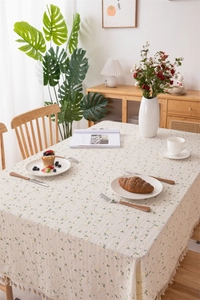 Detail of floral cotton tablecloth featuring beige fringe edges and daisy jacquard patterns
