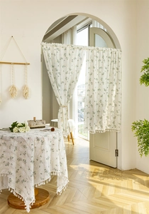 Detailed close-up of white floral embroidery and tassel fringe on cotton door curtain