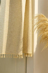 Close-up of beige linen partition curtain with elegant fringe tassels and woven texture