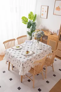Detailed close-up of white cotton tablecloth with black floral embroidery and ruffled edges