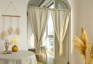 Detailed texture of cream cotton linen curtain with tassel trim and rope tieback