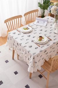 Detail of white cotton tablecloth with black floral embroidery and ruffled edges
