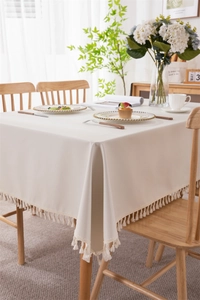 Close-up of beige waterproof PVC tablecloth with decorative cream tassel edge detail