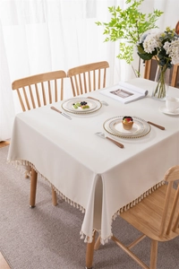 Close-up of cream PVC waterproof tablecloth featuring elegant tassels and a natural drape